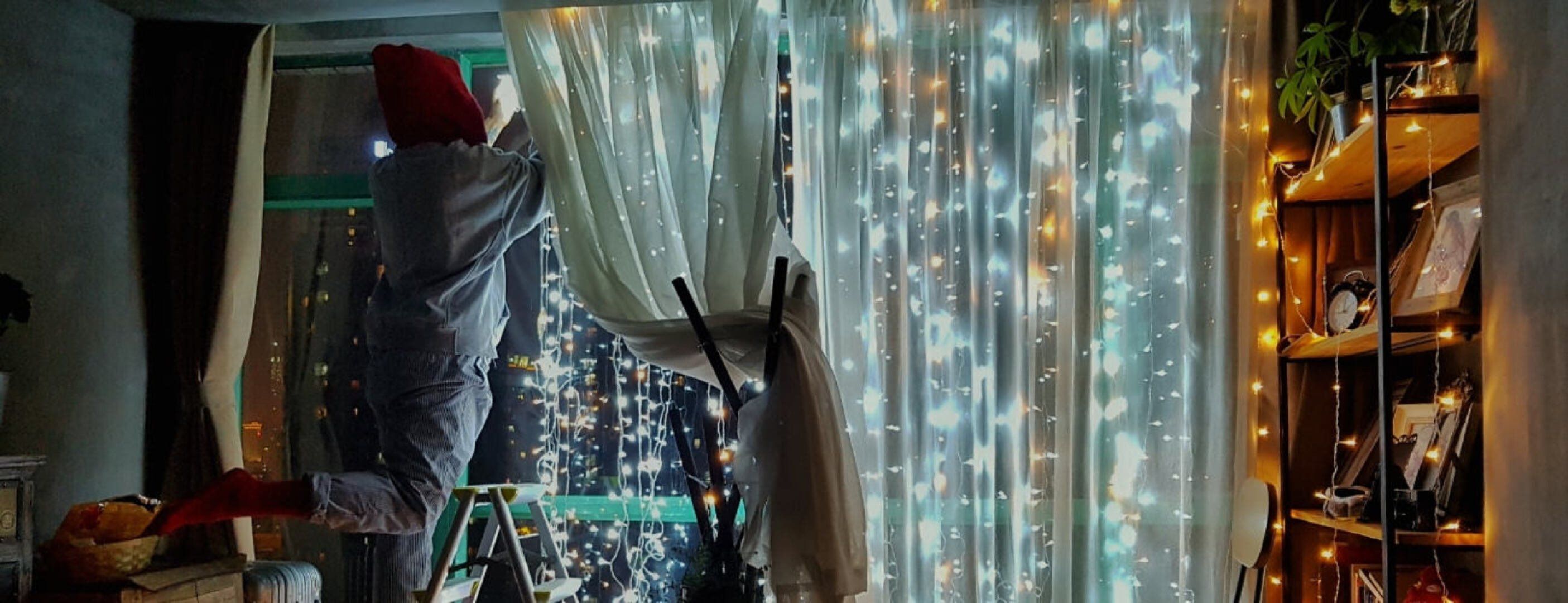 Zu sehen ist eine Person, die nachts Lichterketten aufhängt, welche mit Nachtstrom betrieben werden.