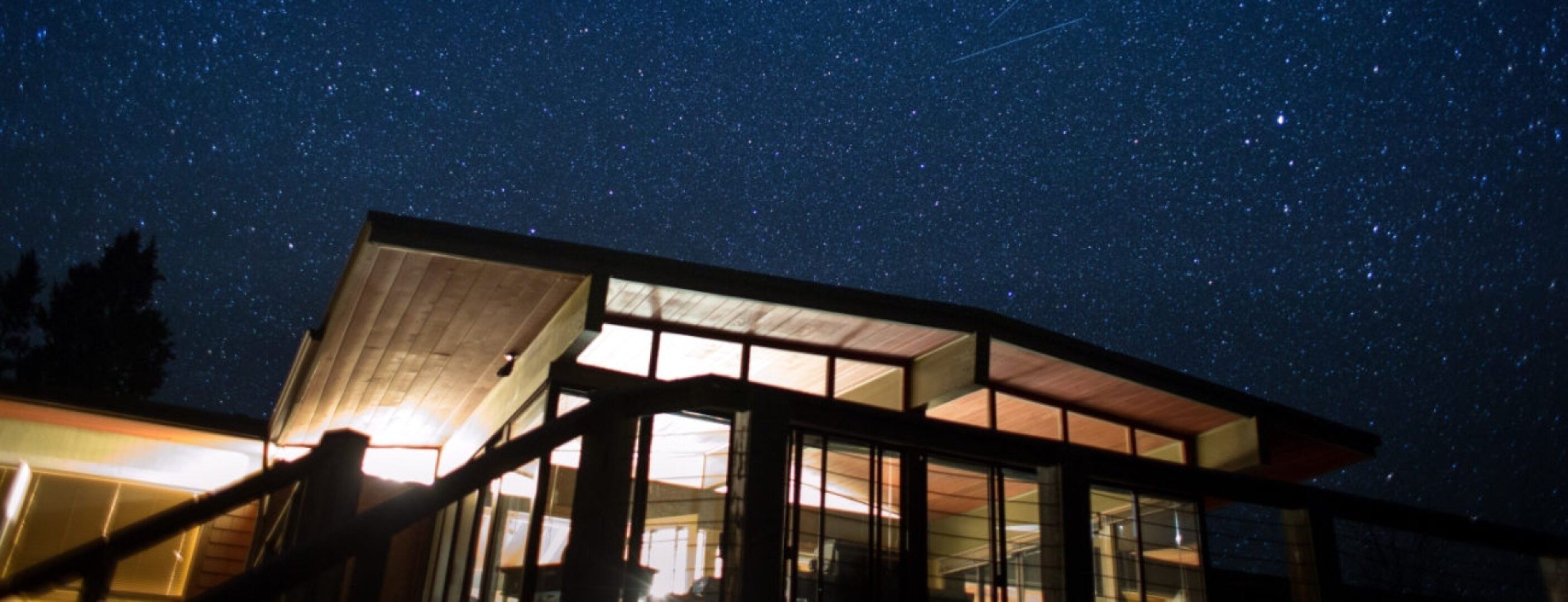Abgebildet ist ein Haus von außen unter dem Sternenhimmel. Die Lichter im Haus brennen dank des Nachtstroms.
