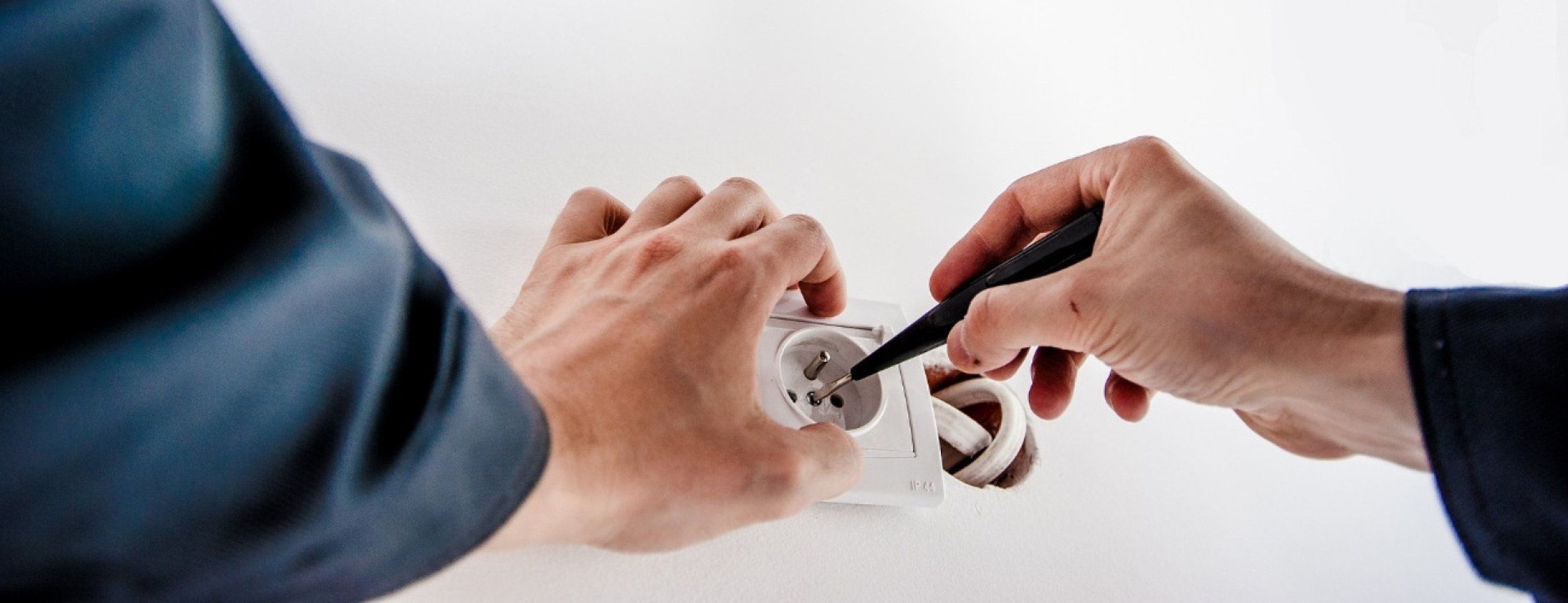 Hier abgebildet ist ein Handwerker, der eine Steckdosemontiert | Energis Ratgeber rund um die Stromeinheiten Watt, Volt und Ampere