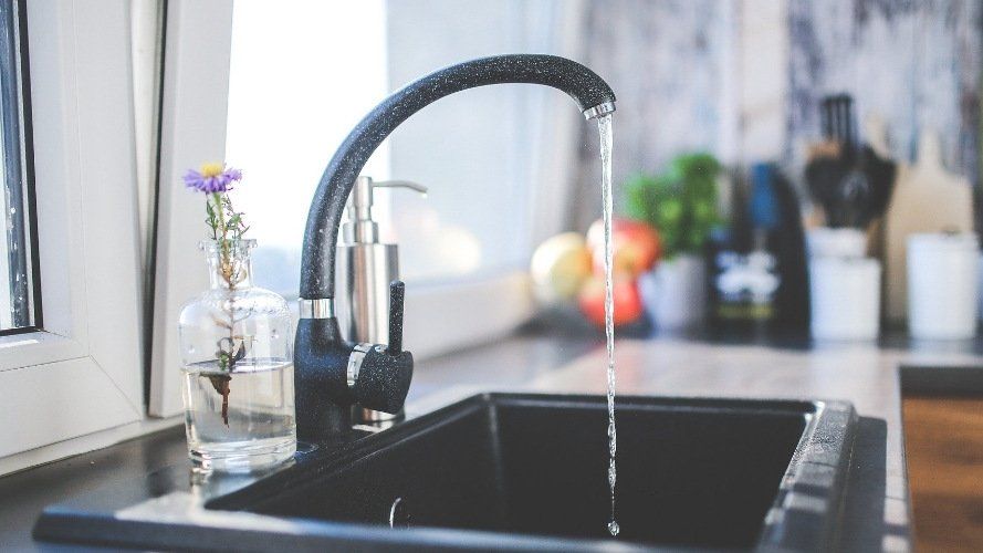 Das Bild zeigt einen laufenden Wasserhahn in einer Küche.