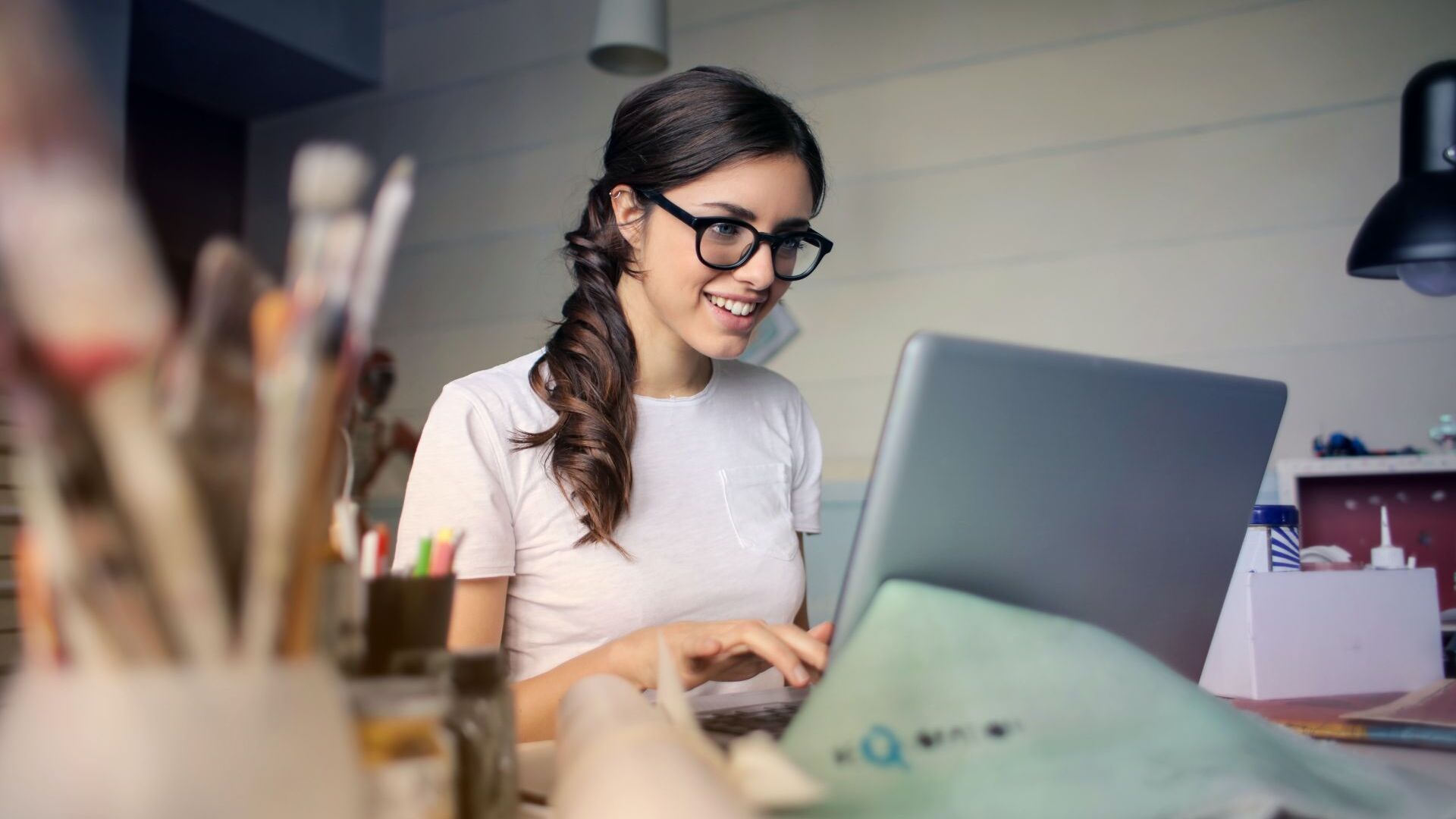 Es ist eine Frau zu sehen, die im Home Office auf ihrem Laptop tippt und wissen will, ob sie Arbeiten im Home Office steuerlich absetzen kann.