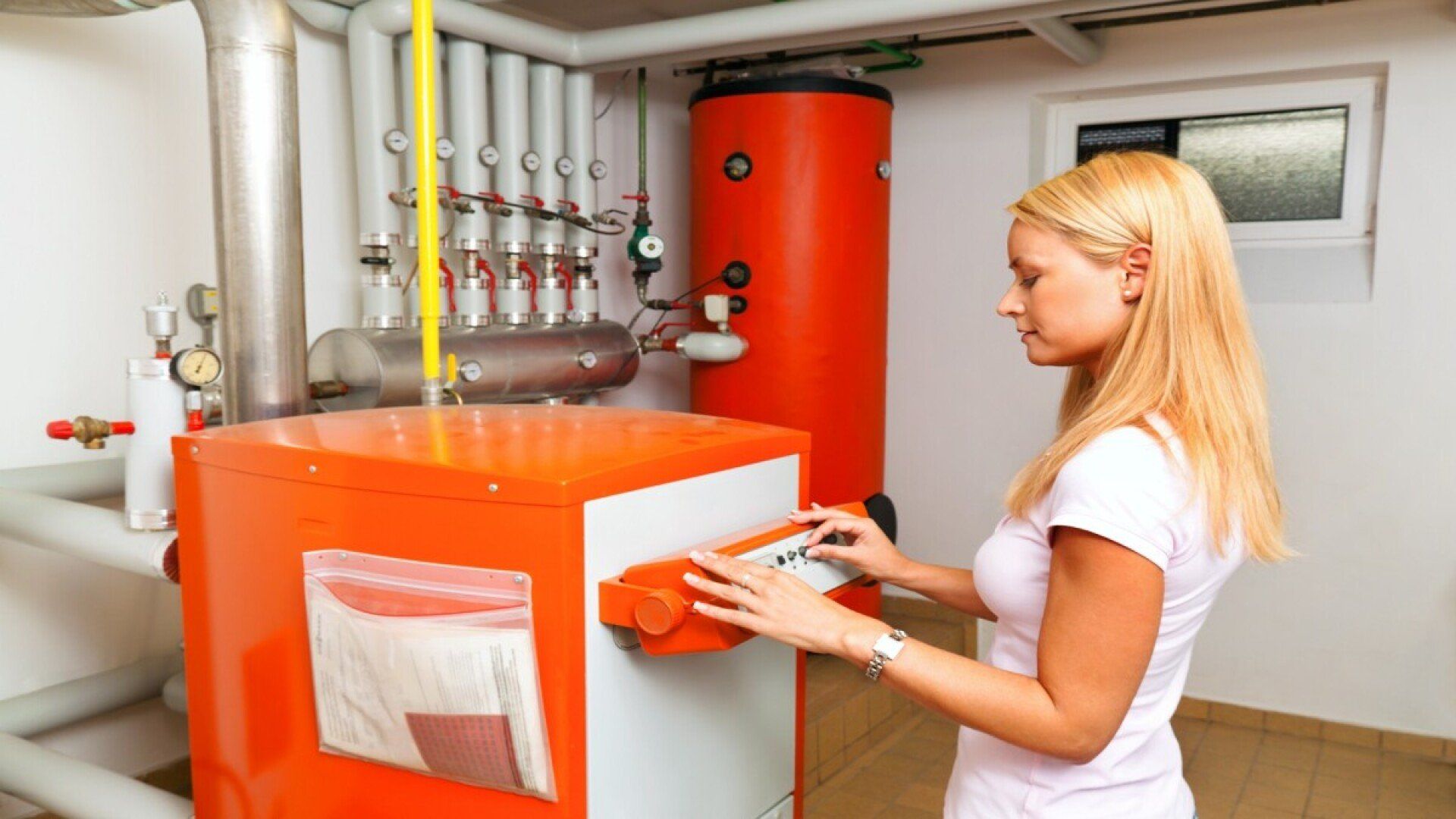 Zu sehen ist eine Frau, die etwas an einer Ölheizung kontrolliert.