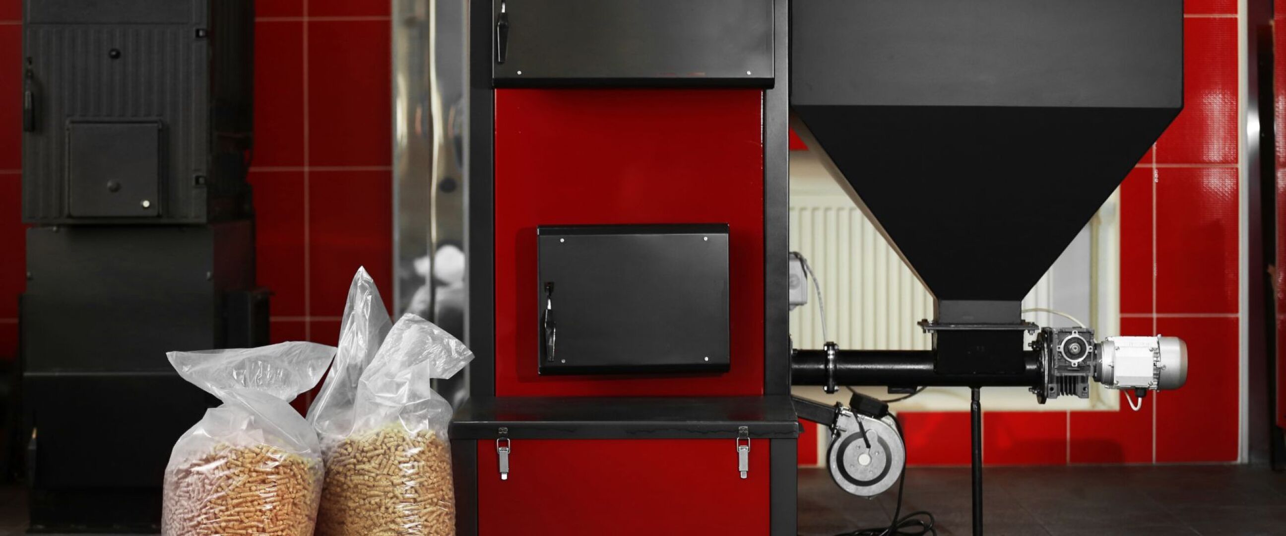 Hier ist eine Pelletheizung-Anlage zu sehen, daneben stehen zwei Säcke mit Pellets.