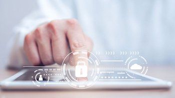 Eine Person tippt auf ein vor ihr liegendes Tablet. Auf dem Bild sind mehrere Symbole miteinander verbunden. Zu sehen ist ein geschlossenes Schloss, eine Wolke und ein Männchen.