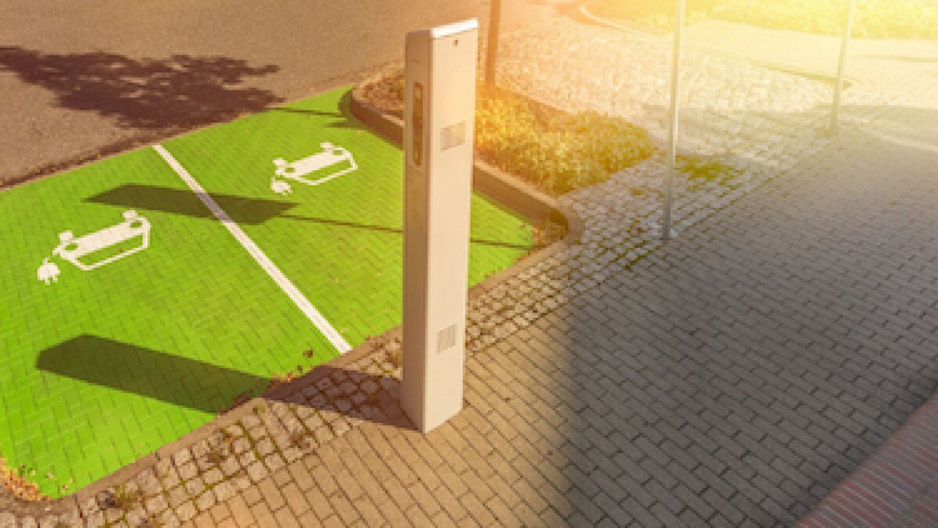 Auf dem Bild steht eine E-Ladesäule auf zwei grün markierten E-Auto-Parkplätzen.