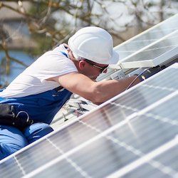 Zu sehen ist ein Mann, der eine Solaranlage auf einem Dach wartet.