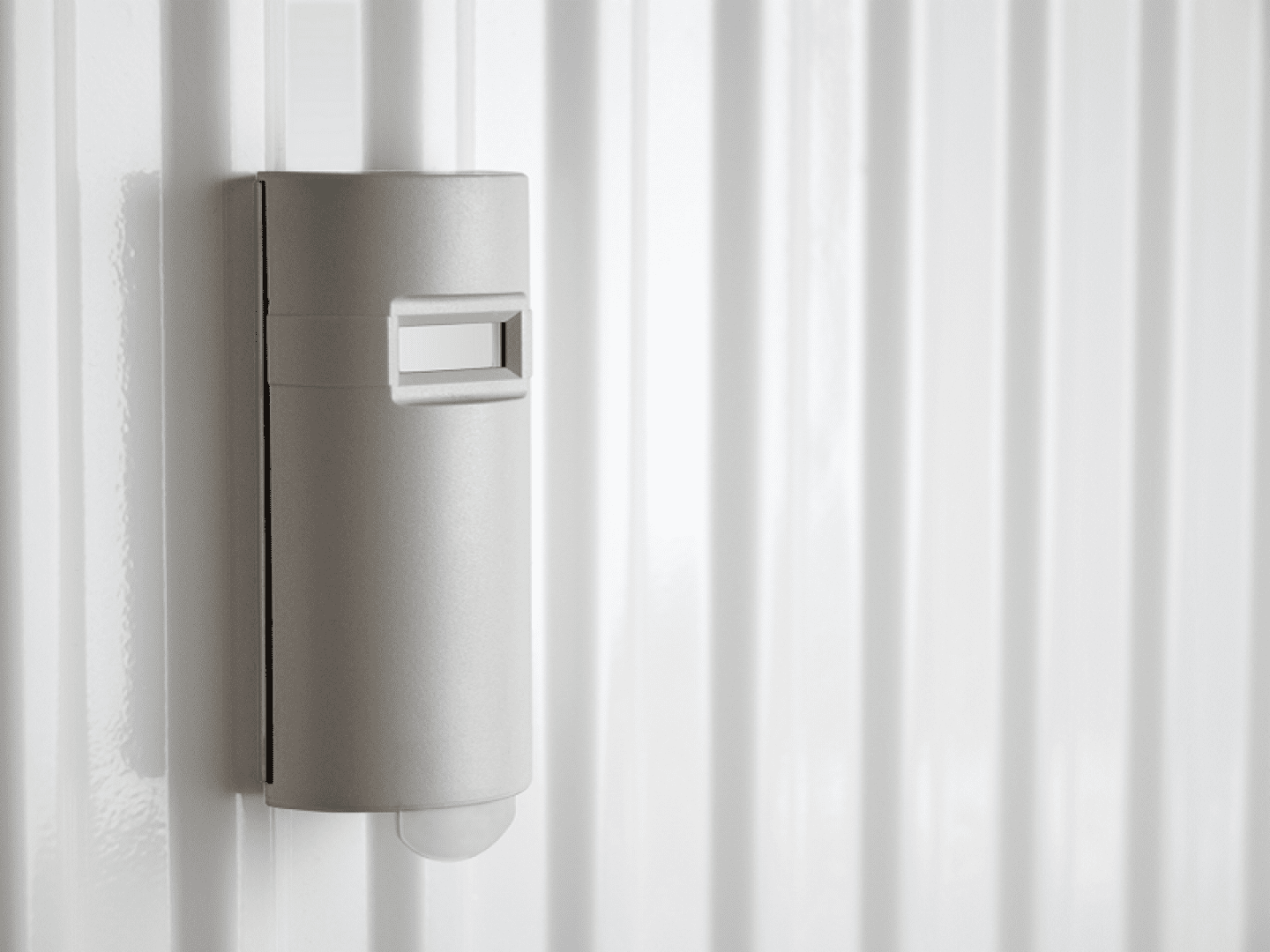 Ein elektronischer Heizkostenverteiler hängt an einem Heizkörper.