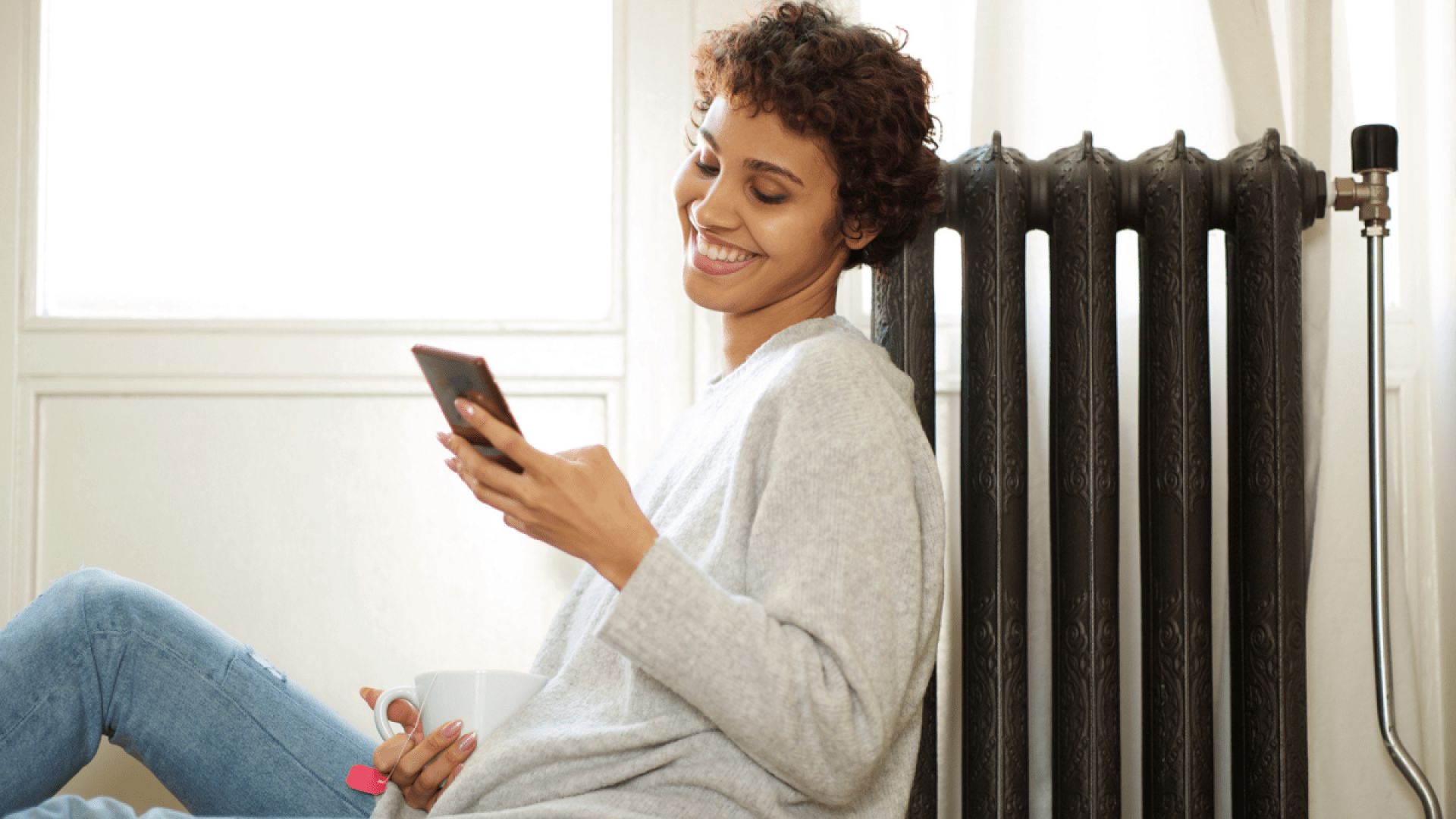 Eine Frau wärmt sich an der Heizung, nachdem die Heizungswartung durchgeführt wurde.