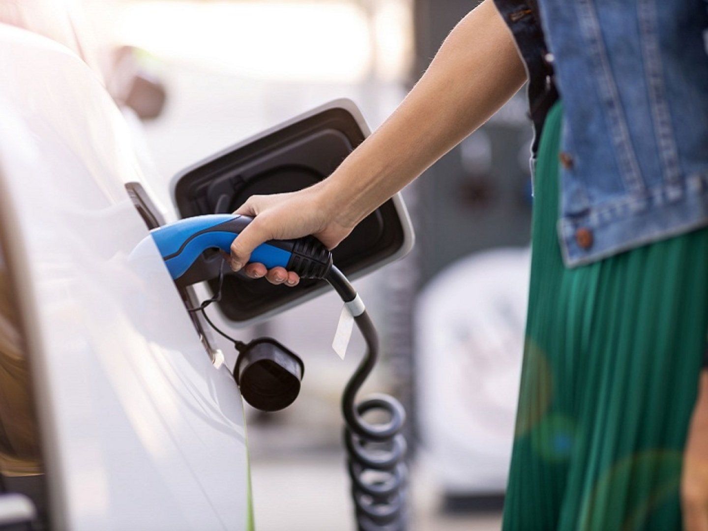 Eine Frau testet das Laden eines E-Autos, da sie überlegt ein E-Auto zu kaufen oder zu leasen.