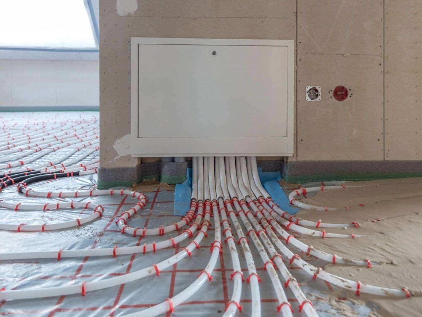 Rohre einer Fußbodenheizung werden mit Estrich bedeckt.