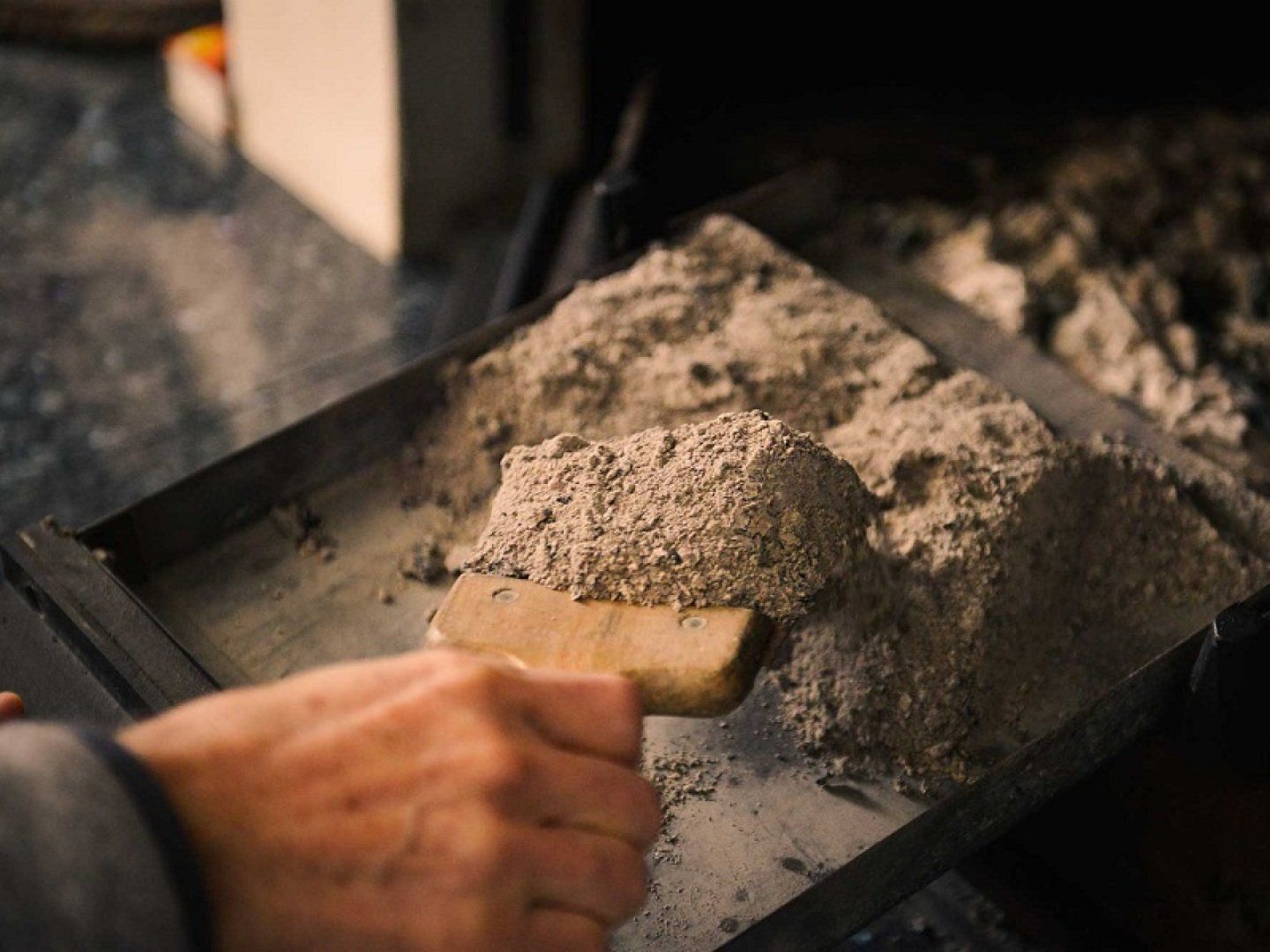 Eine Person entsorgt die Asche aus einem Kamin.