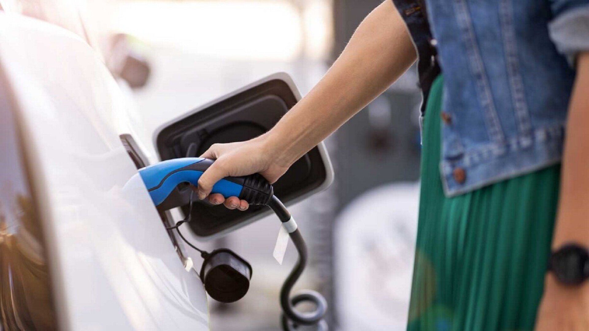 Eine Frau lädt ihr Elektroauto und bekommt die THG-Quote für E-Autos.