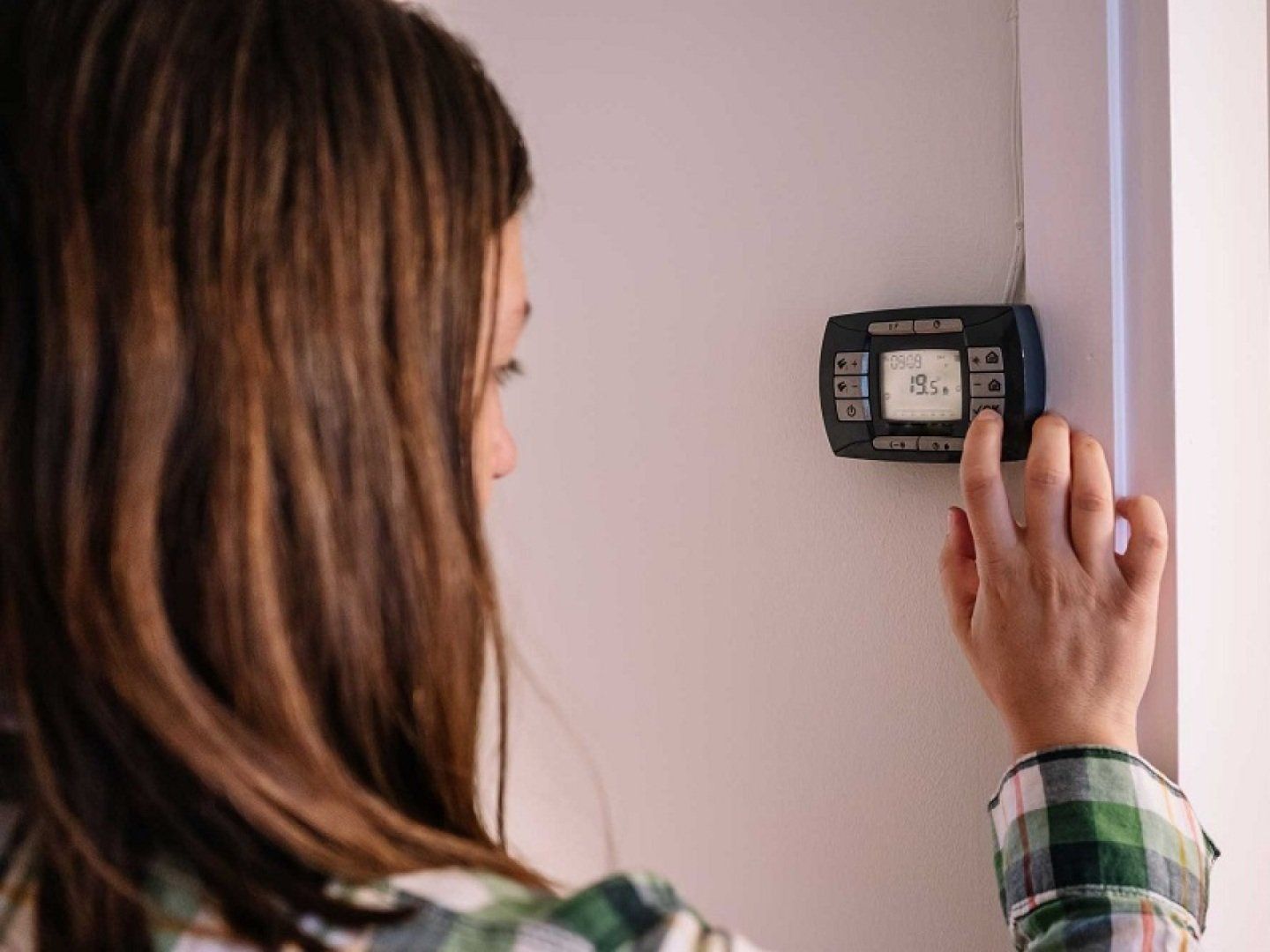 Eine Frau reduziert die Temperatur ihrer Heizung im Rahmen des Notfallplans Gas.