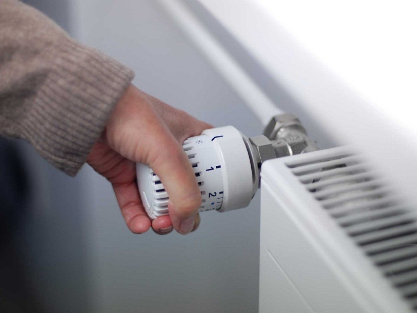 Eine Frau dreht im Rahmen der Stufen im Notfallplan Gas die Heizung runter.