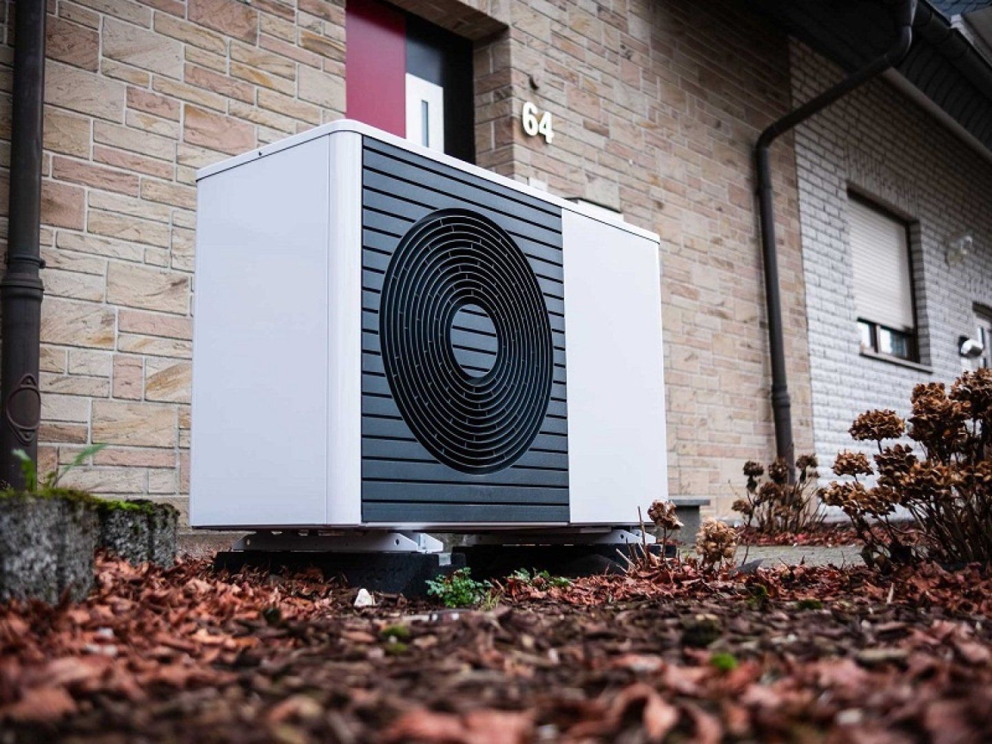 Eine Luftwärmepumpe steht vor einem Altbau.