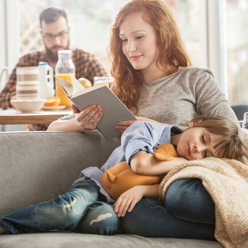 Mutter und Tochter gemütlich in Decke gehüllt zuhause am Fenster, warme Umgebung
