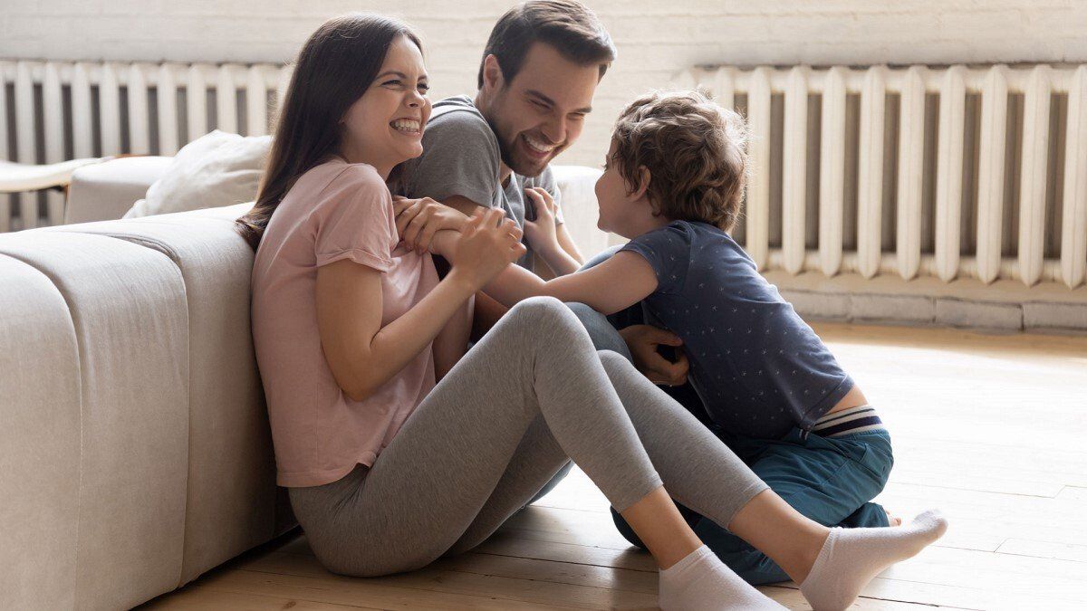 Familie Mutter Vater Kind in Wohnzimmer vor Heizung