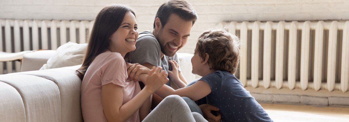 Familie Mutter Vater Kind in Wohnzimmer vor Heizung