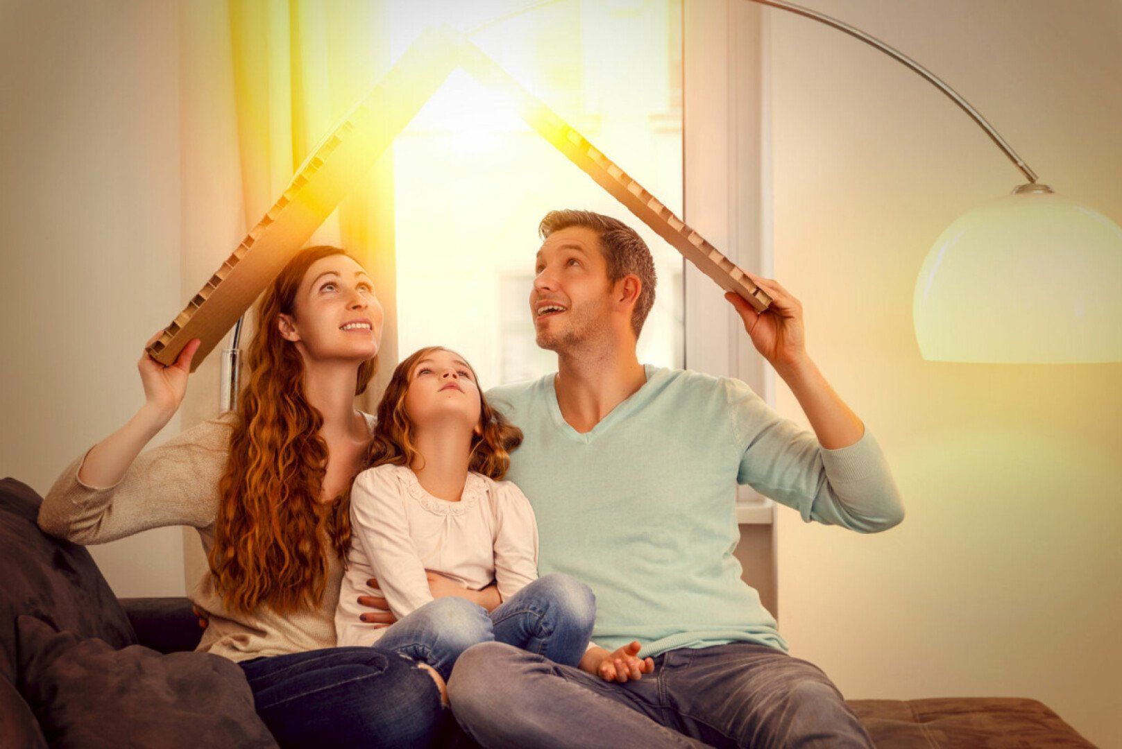 Familie sitzt auf Sofa unter Pappdach und die Sonne scheint durch