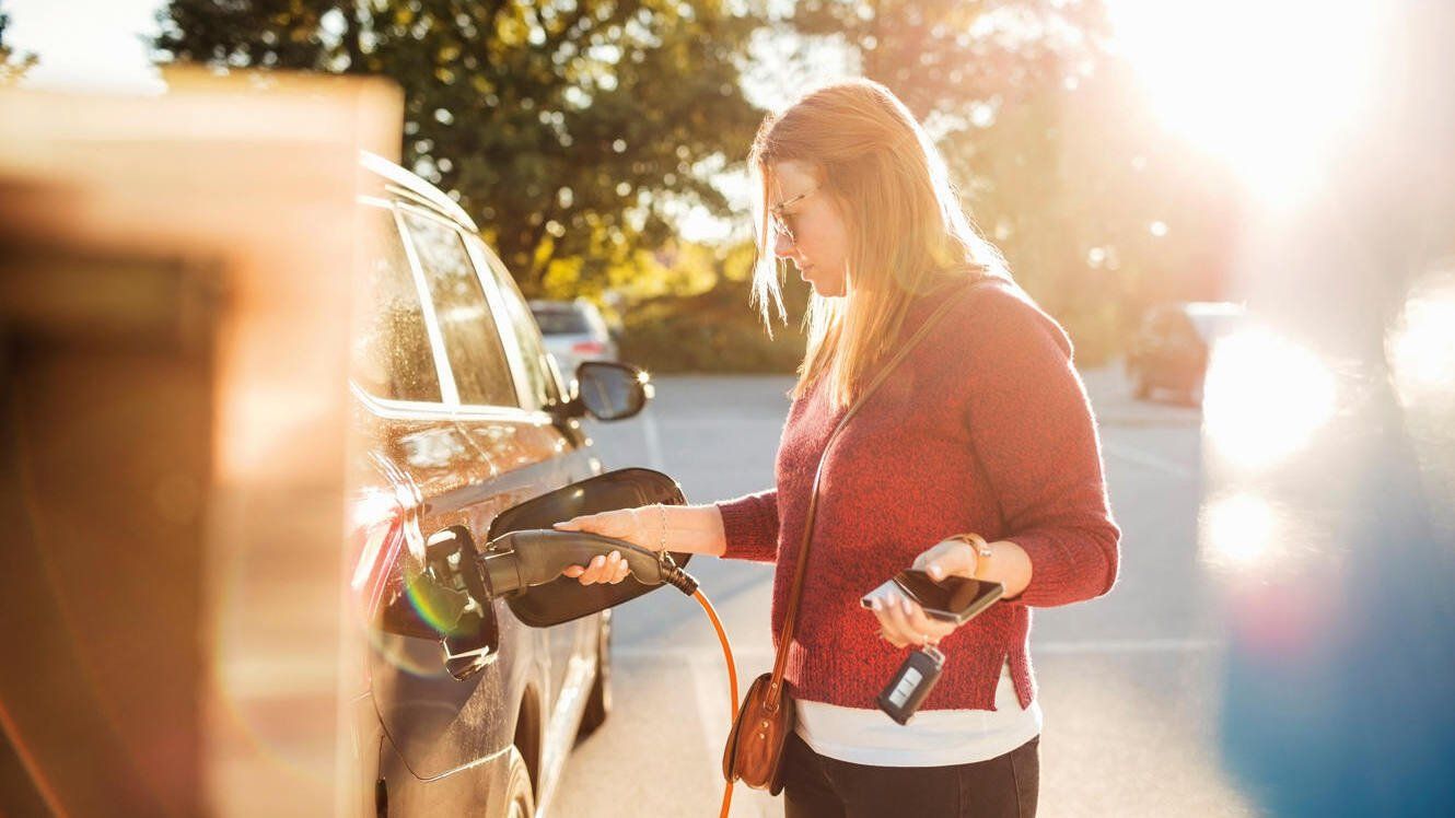 Frau lädt Eauto an öffentlicher Ladestation