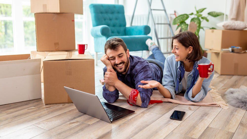 Paar am vor Laptop und Umzugskisten