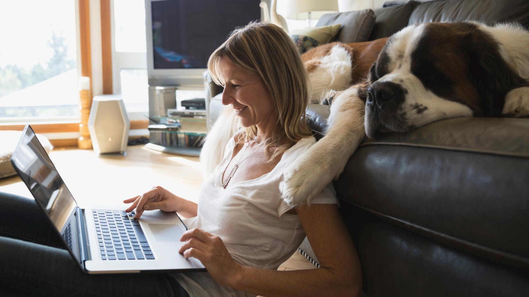 Frau mit Hund schaut in Laptop