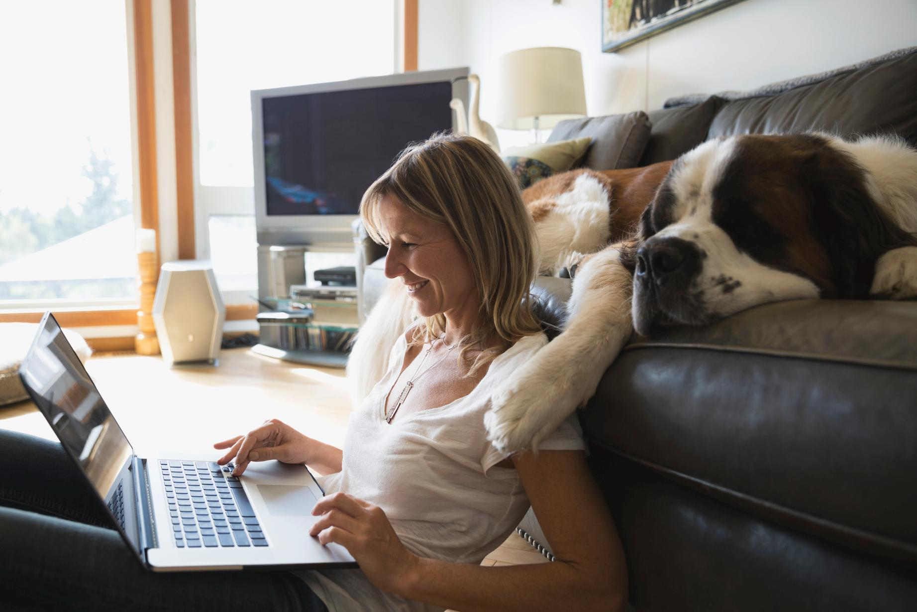 Frau mit Hund schaut in Laptop