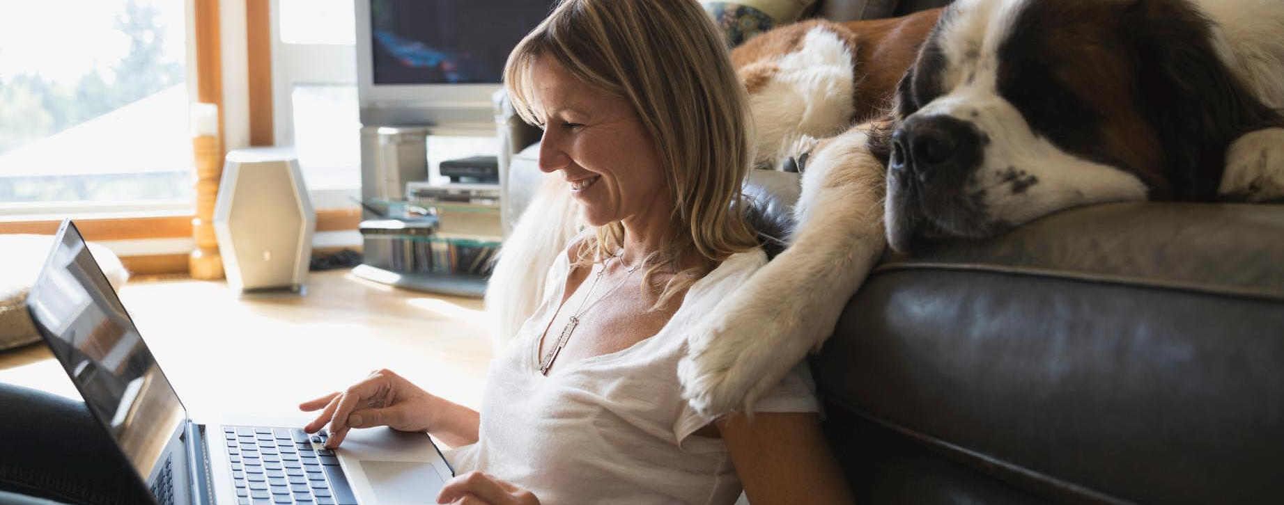 Frau mit Hund schaut in Laptop