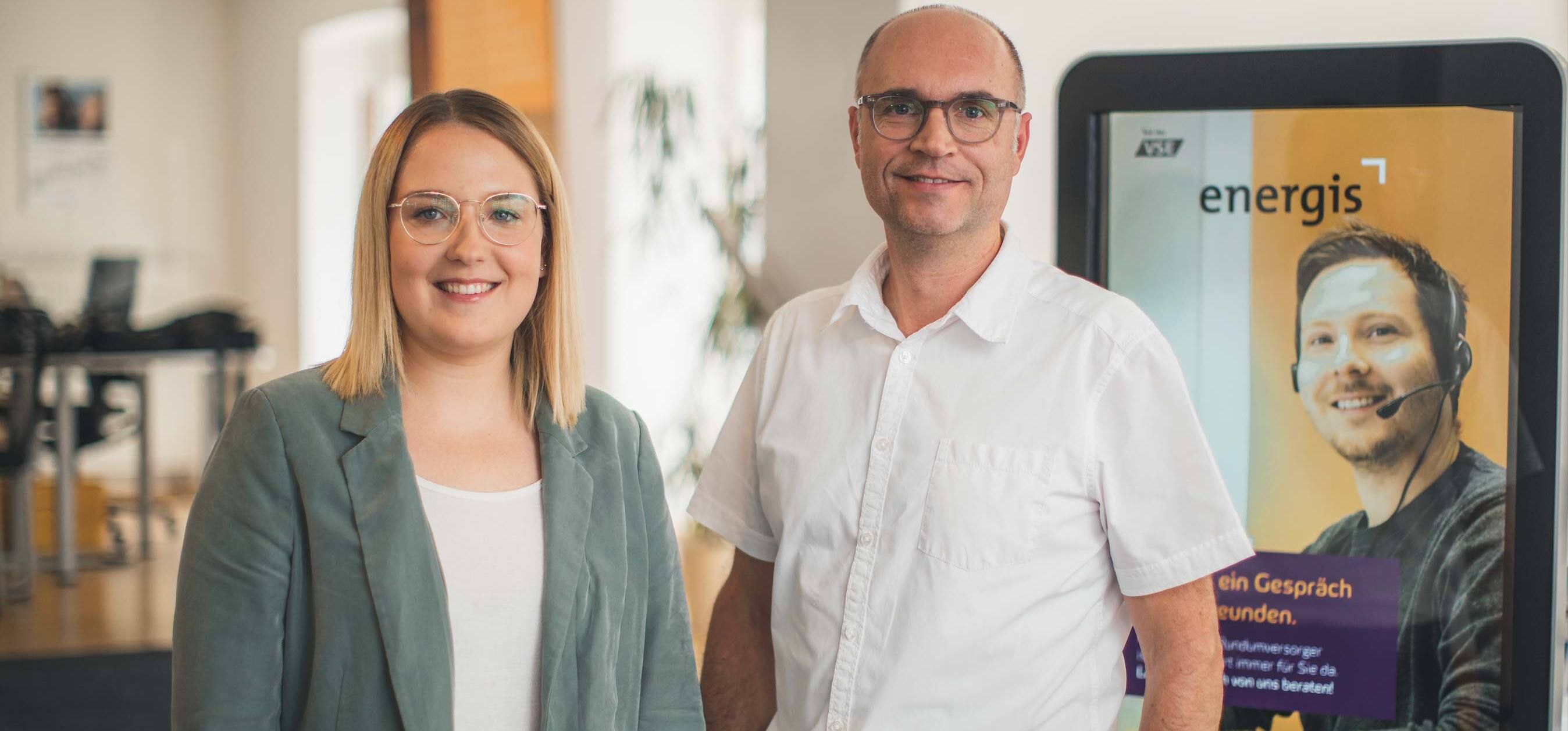 energis Kundenberater im Kundencenter vor Infostele