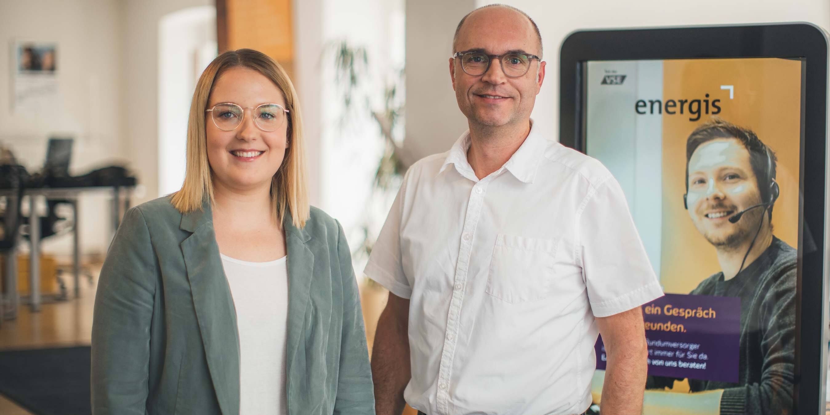 energis Kundenberater im Kundencenter vor Infostele