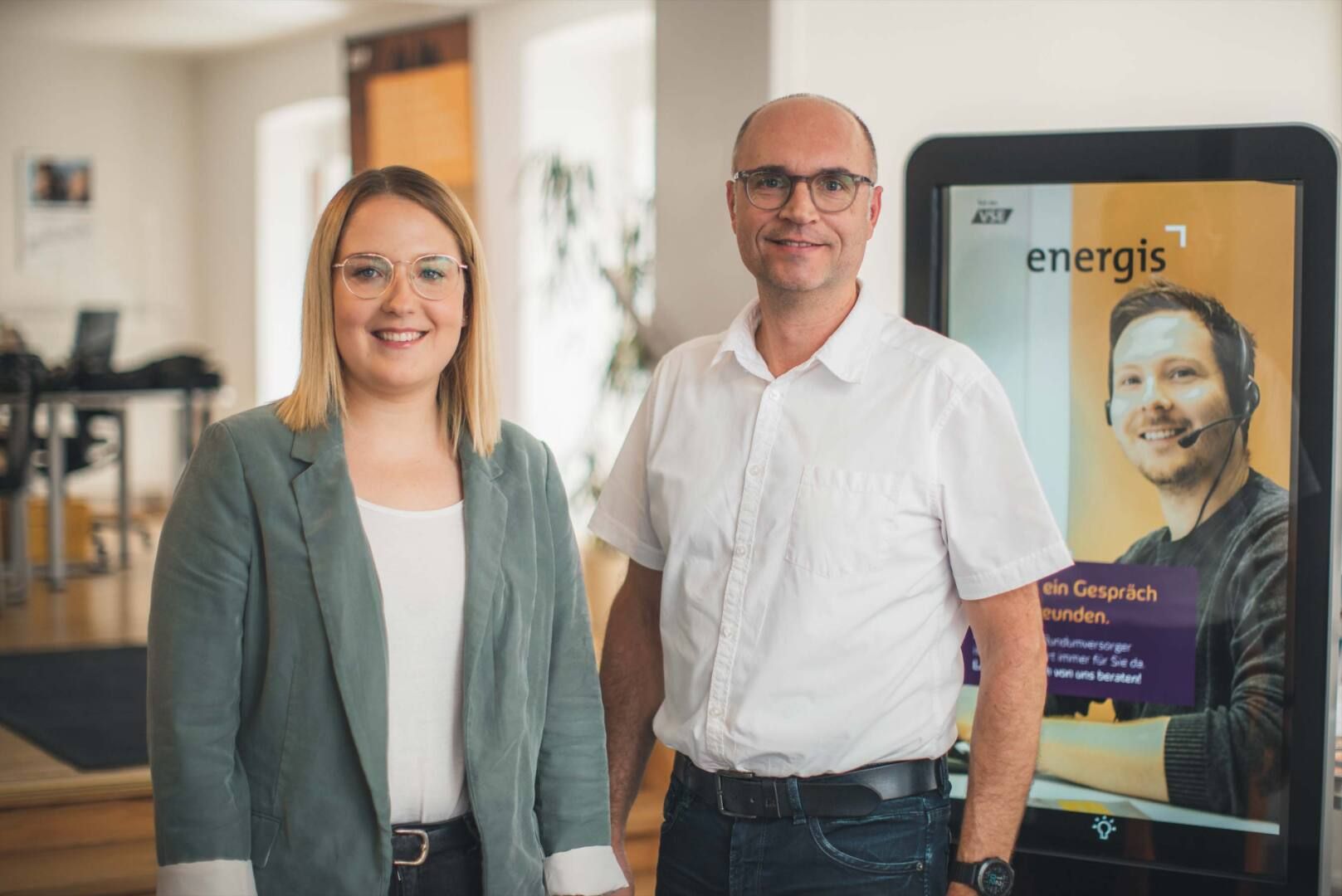 energis Kundenberater im Kundencenter vor Infostele