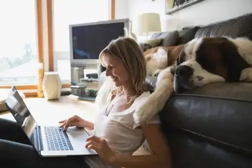 Frau mit Hund schaut in Laptop