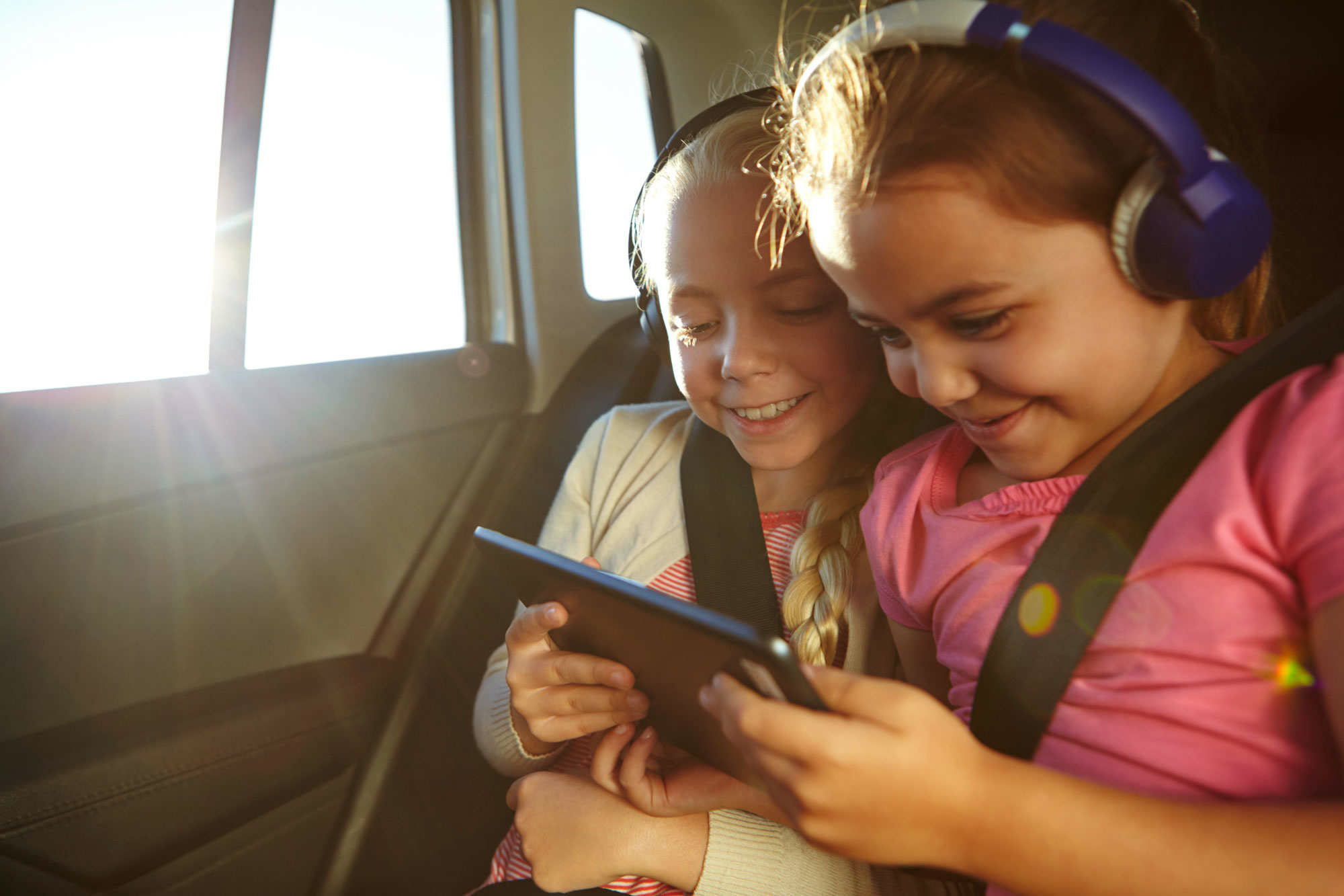 Kinder mit Tablet und Kopfhörer im Auto