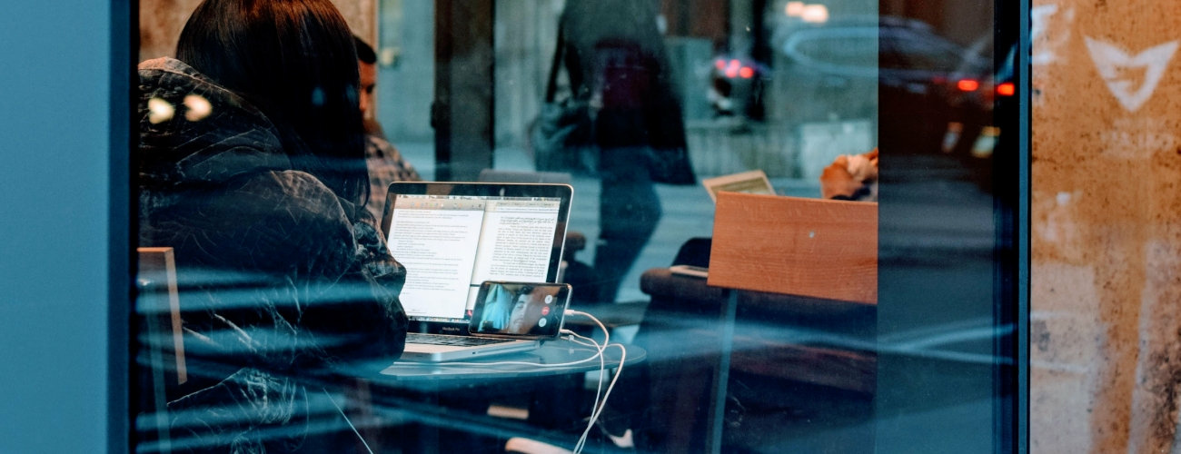 Eine junge Frau führt über VoIP mit ihrem Smartphone in einem Café ein Videogespräch mit ihrem Freund