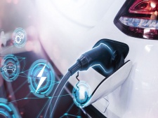 Die Grafik zeigt einen Ladestecker während des Ladens eines E-Autos. Daneben einige Symbole in blauen Kreisen z. B. ein Blitz, eine Akkuanzeige und Zahnräder. 