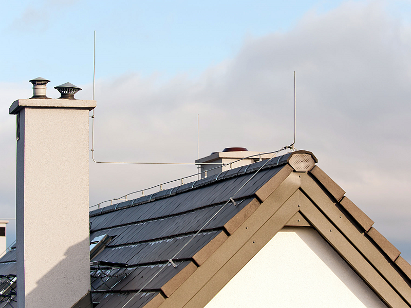 Das Bild zeigt einen Blitzableiter auf dem Dach eines Hauses. 