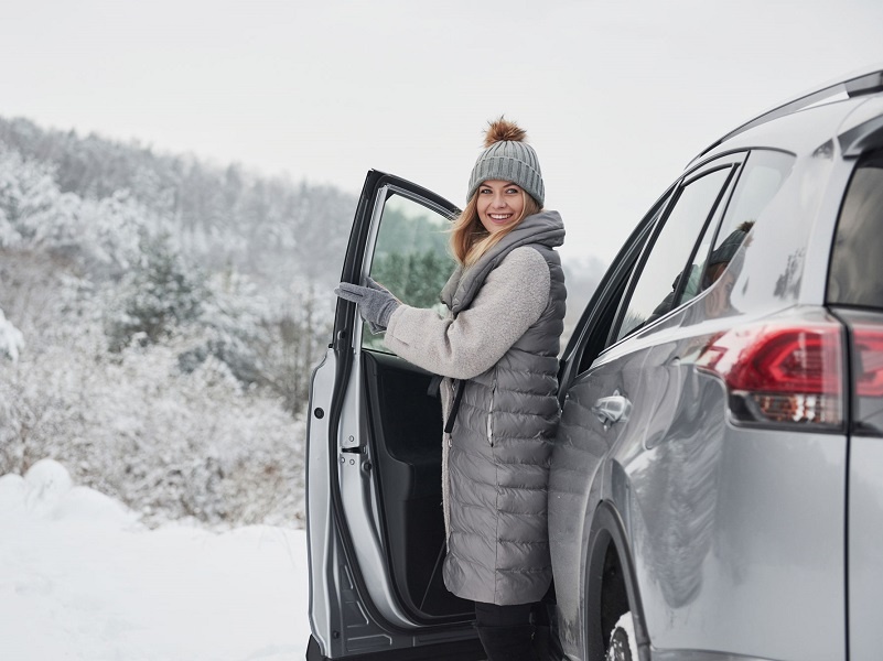 Eine Frau steigt aus einem E-Auto im Winter.